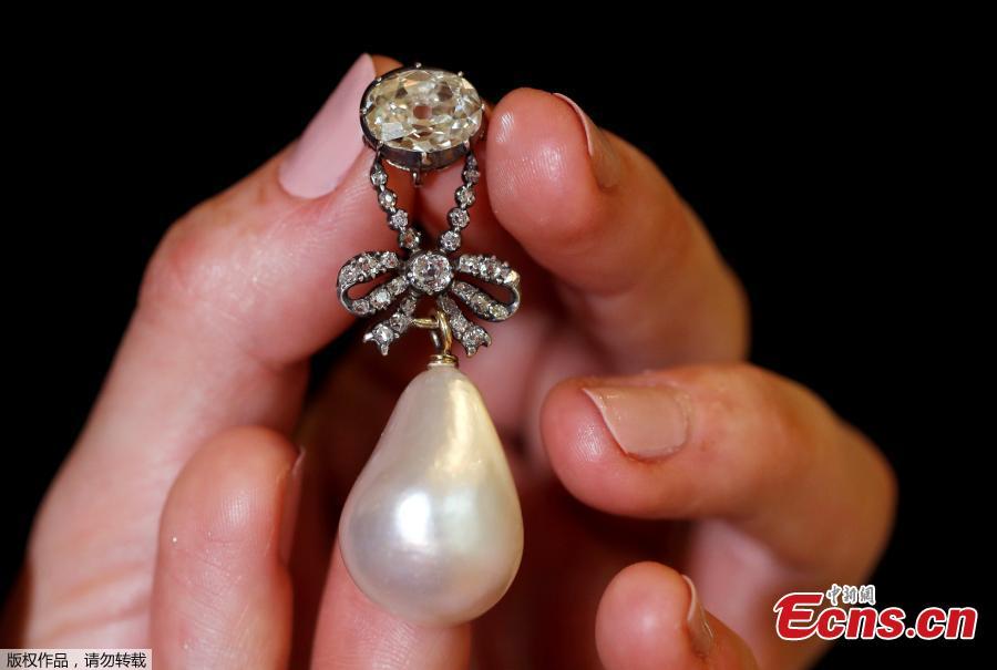 A natural pearl and diamond pendant once owned by Marie Antoinette is held by a model during a press preview ahead of the upcoming auction \