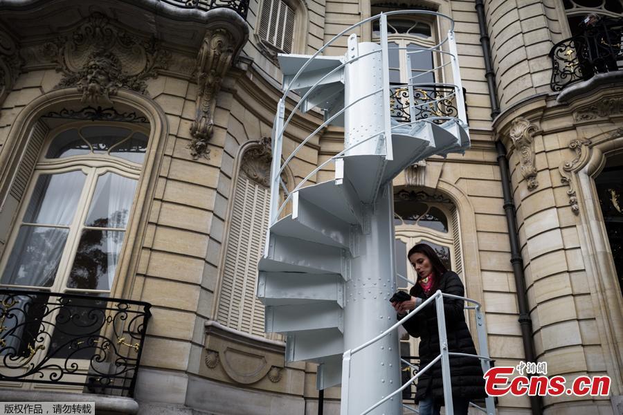 A woman stands on a section of stairs from the Eiffel Tower original structure displayed outside the Artcurial French auction house ahead of its forthcoming sale in Paris on November 8, 2018. (Photo /Agencies)