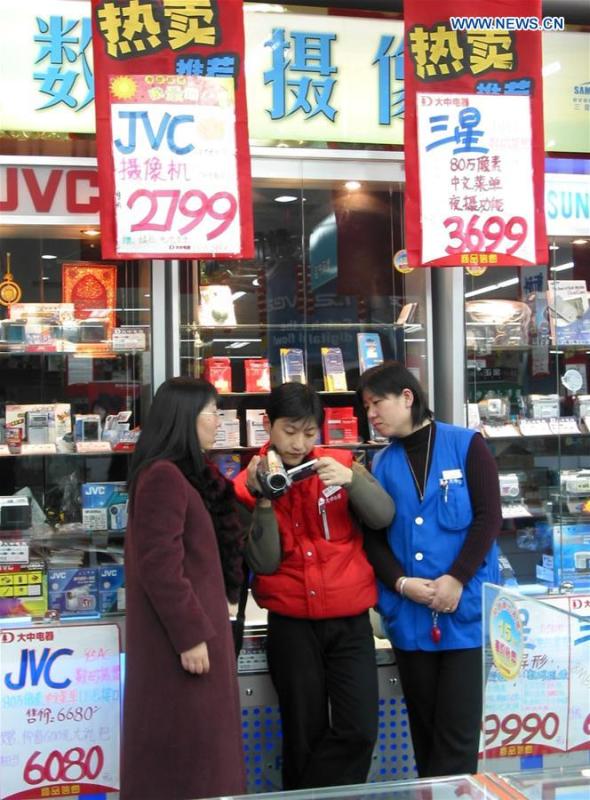 File photo taken on Nov. 27, 2003 shows staff members helping a customer adjust digital camera at an electric device shop in Beijing, capital of China. (Xinhua/Pang Xinglei)