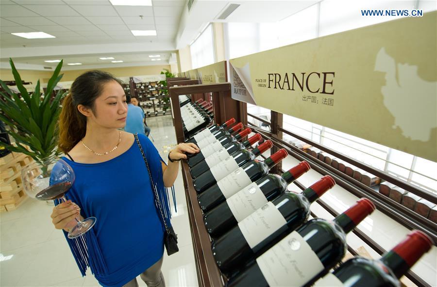 A woman looks at red wine imported from France at the first Chongqing international red wine cultural festival in Chongqing, southwest China, Sept. 2, 2012. (Xinhua/Liu Chan)