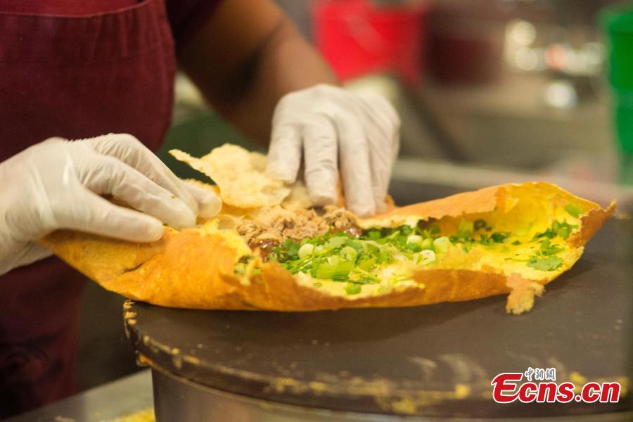 A worker makes Jianbing, or the Chinese crepe at a kiosk in a food court in Brooklyn, New York, the United States on November 10, 2018. The Chinese snack ranges in cost from $13 to $15. (Photo: China News Service/ Liao Pan)