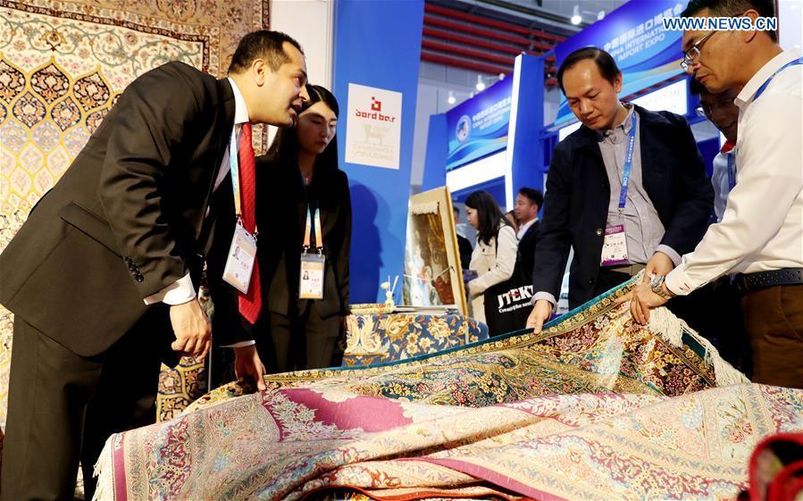 An Iranian exhibitor (L) introduces carpets at the First China International Import Expo in Shanghai, east China, Nov. 5, 2018. (Xinhua/Fang Zhe)