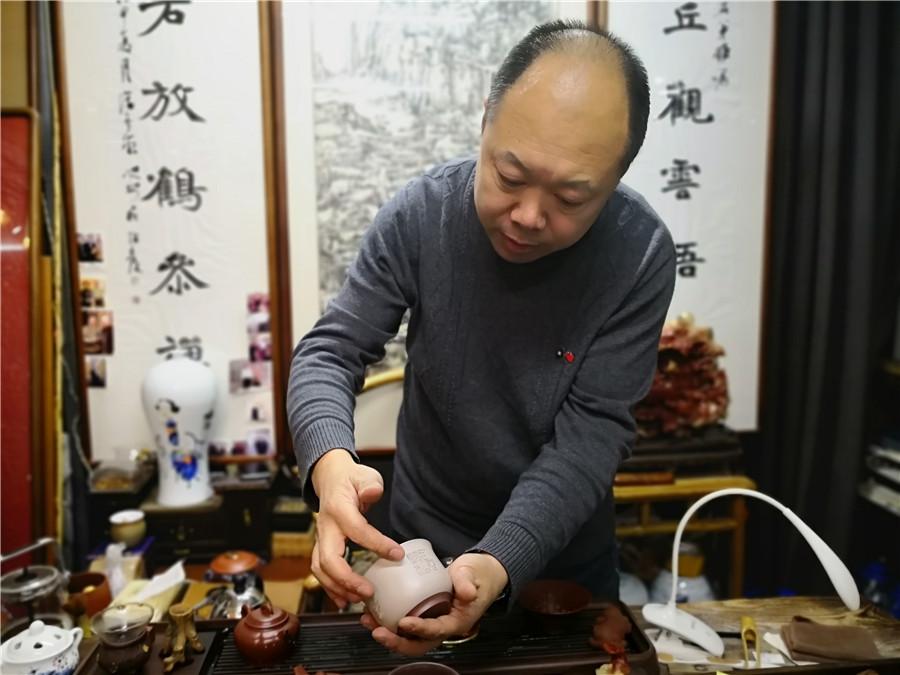 Zhao Qiushi presents a microscopic carving work on a tea cup. (Photo/chinadaily.com.cn)
In the past 10 years, Zhao Qiushi has created more than 2,000 pieces of microscopic carvings in Changchun, capital city of Northeast China\'s Jilin Province.
Zhao, 46, who runs an artwork studio in Changchun, created his first piece upon a customer\'s request in 2009.
The artist, who learned the traditional Chinese artistic techniques in university, provided the customer within five days a 30-millimeter stone ornament carved with the Heart Sutra, a popular Buddhist scripture which includes 260 Chinese characters.
Since then, he has been engaged in creating such carvings of Chinese classical literature works.
His most exquisite work is a piece of 2-square-centimeter stone caved with the Heart Sutra.
\