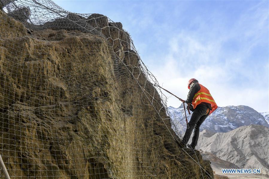 A construction worker installs protective nets on a cliff at a road section in the Tajik Autonomous County of Taxkorgan, northwest China\'s Xinjiang Uygur Autonomous Region, Nov. 12, 2018. The job of this team of construction workers is to install protective facilities on the cliff of risky road sections in the mountainous areas in Xinjiang, protecting pedestrians and vehicles from fallen stones. (Xinhua/Hu Huhu)