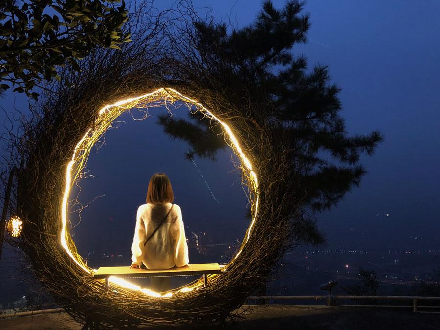 A visitor takes a picture inside the Bali bird nest at Chongqing Night View Park on Nov. 10, 2018. (Photo provided to chinadaily.com.cn)
A themed park featuring night scenes recently opened to the public on Nanshan Mountain in Chongqing, a city in Southwest China also surrounded by the Yangtze and Jialing rivers.
Visitors to Chongqing Night View Park can enjoy a 270-degree panorama view of the two rivers and the Yuzhong Peninsula. The park features seven themed photo spots, such as a giant bird nest, a Bali bird nest, a dream kitchen, a heart house and star bubble house.
The park attracted a lot of visitors since opening Nov. 10, and some young people have even proposed at the Star bubble house, according to park staff.