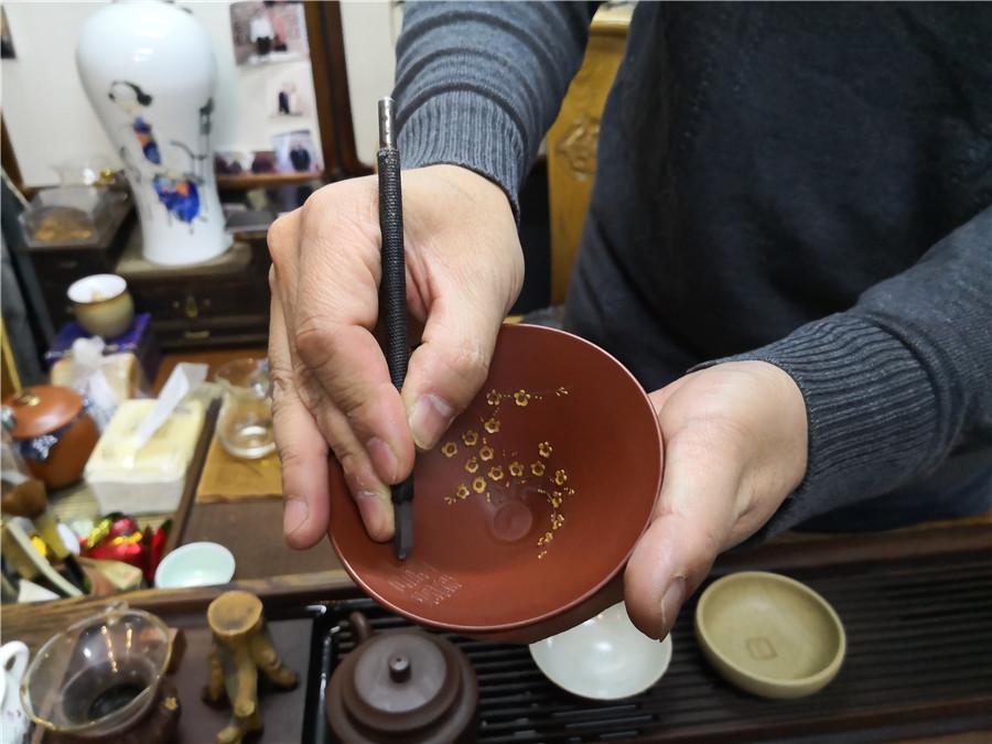 Zhao Qiushi creates the artworks of microscopic carving on a dark-red enameled pottery conditioner. (Photo/chinadaily.com.cn)