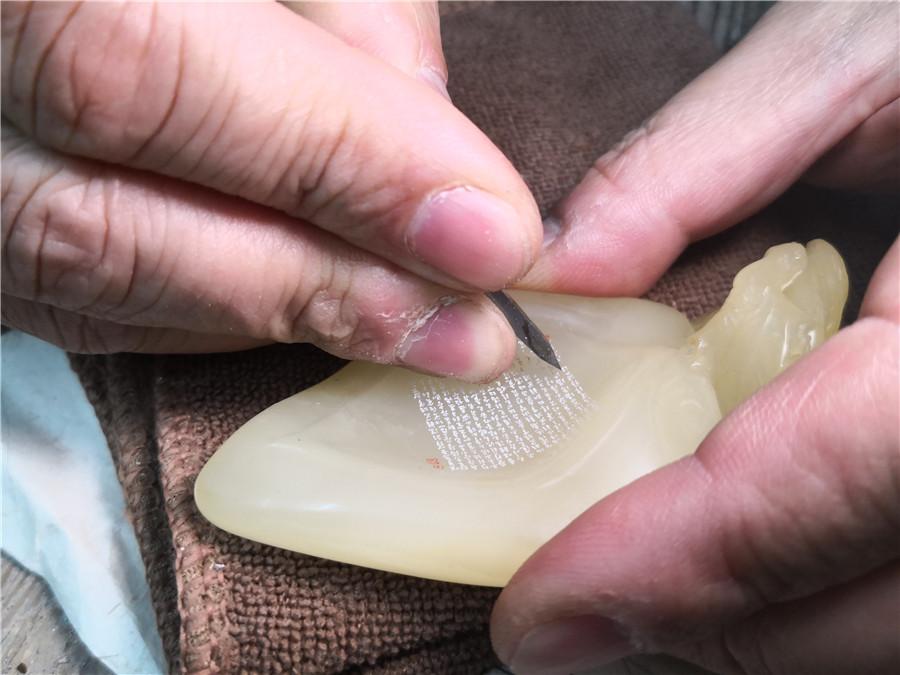 Zhu Qiushi chooses the traditional needle for a microscopic carving.  (Photo/chinadaily.com.cn)