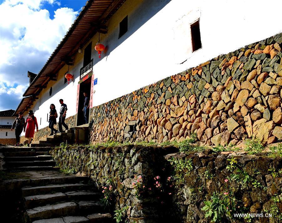 Tourists visit the Aijing Zhuang residential complex in Yangwei Village of Yongtai County, southeast China\'s Fujian Province, Nov. 11, 2018. The project, with a total of 361 rooms covering the area of over 5,200 square meters, was built during the reign of Emperor Daoguang in the Qing Dynasty. It has safeguarded the authentic character of the vernacular housing, defensive structures and waterways that are emblematic of this site, providing a model for other historic villages across China. The conservation of Aijing Zhuang residential complex demonstrates a sensitive approach to sustaining a rural settlement as a living place in harmony with its natural setting. Aijing Zhuang in November this year received the Award of Merit in the 2018 UNESCO Asia-Pacific Awards for Cultural Heritage Conservation. (Xinhua/Zhang Guojun)