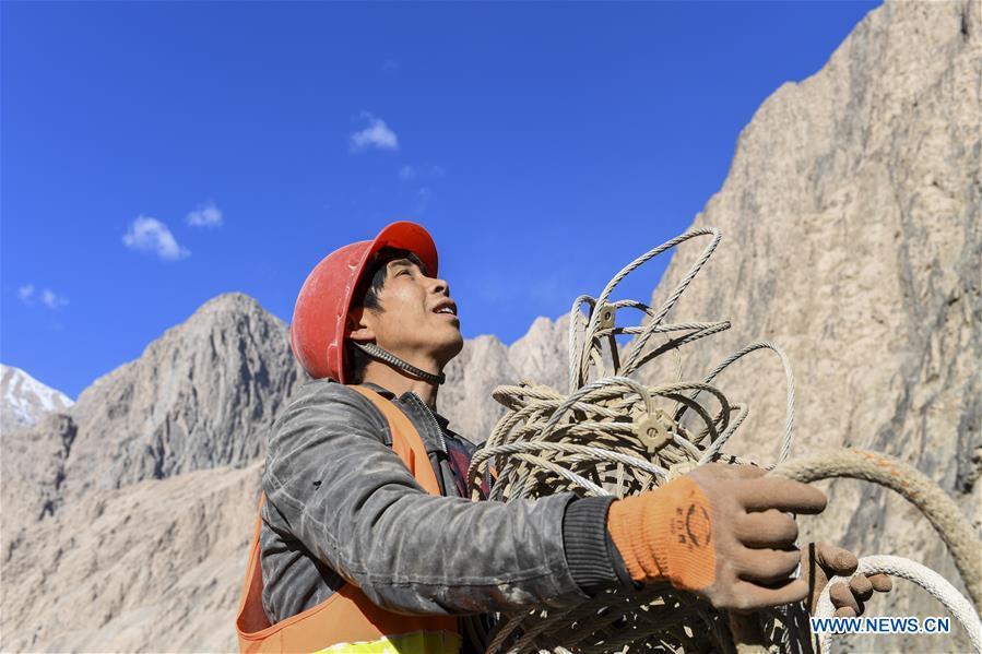 Construction worker Wang Huaguo transfers protective nets on a cliff at a road section in the Tajik Autonomous County of Taxkorgan, northwest China\'s Xinjiang Uygur Autonomous Region, Nov. 12, 2018. The job of this team of construction workers is to install protective facilities on the cliff of risky road sections in the mountainous areas in Xinjiang, protecting pedestrians and vehicles from fallen stones. (Xinhua/Hu Huhu)