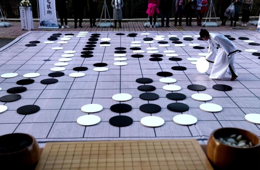 A player places a piece on Monday during a game of go on the sidelines of the finals of the third Chinese Weiqi Sage Title competition on Luoyang\'s Baiyun mountain in Henan Province. Renowned go players Zhou Ruiyang and Lian Xiao posed for pictures with young players. (Photo/Asianewsphoto)