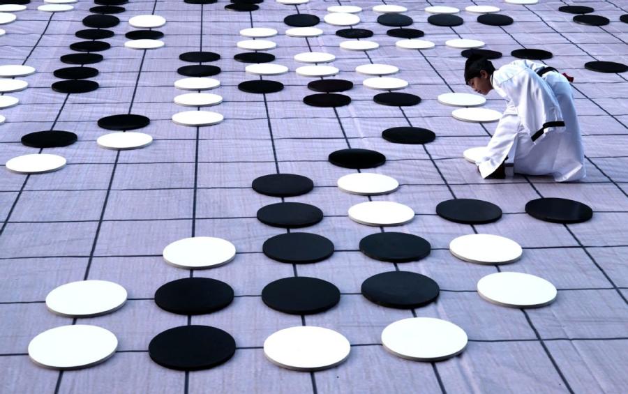 A player places a piece on Monday during a game of go on the sidelines of the finals of the third Chinese Weiqi Sage Title competition on Luoyang\'s Baiyun mountain in Henan Province. (Photo/Asianewsphoto)