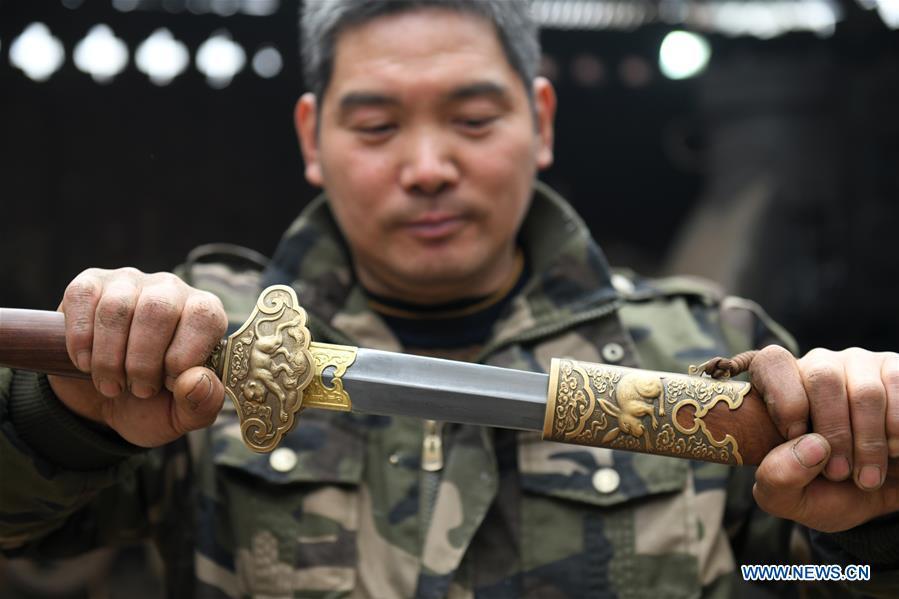 Li Zhujun shows a decorative sword made by him at his studio in Tiejiangzhuang Village of Xingtang County, Shijiazhuang, north China\'s Hebei Province, Nov. 14, 2018. For centuries, Tiejiangzhuang Village has been famed for its skillful blacksmiths and prosperous steel making industry. Li Zhujun is one of the village\'s top steel makers. Based on the skills inherited from his father, Li gained an expertise in the steel-making technique \