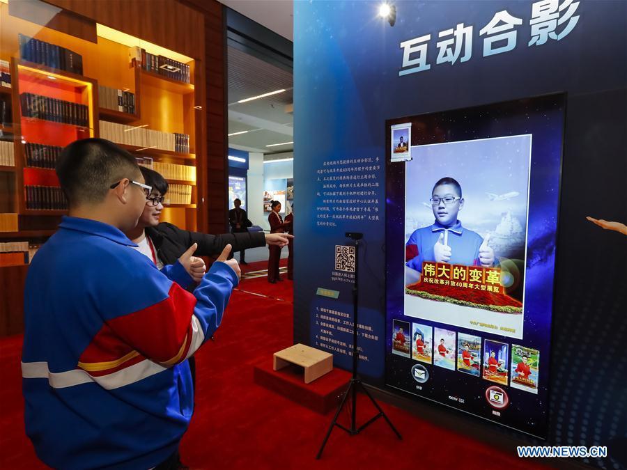 A student poses for photos at a multimedia interactive zone during a major exhibition to commemorate the 40th anniversary of China\'s reform and opening-up held at the National Museum of China in Beijing, capital of China, Nov. 14, 2018. The exhibition opened here on Tuesday. (Xinhua/Shen Bohan)