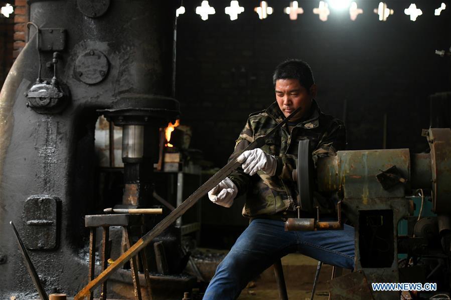 Li Zhujun makes a decorative sword at his studio in Tiejiangzhuang Village of Xingtang County, Shijiazhuang, north China\'s Hebei Province, Nov. 14, 2018. For centuries, Tiejiangzhuang Village has been famed for its skillful blacksmiths and prosperous steel making industry. Li Zhujun is one of the village\'s top steel makers. Based on the skills inherited from his father, Li gained an expertise in the steel-making technique \