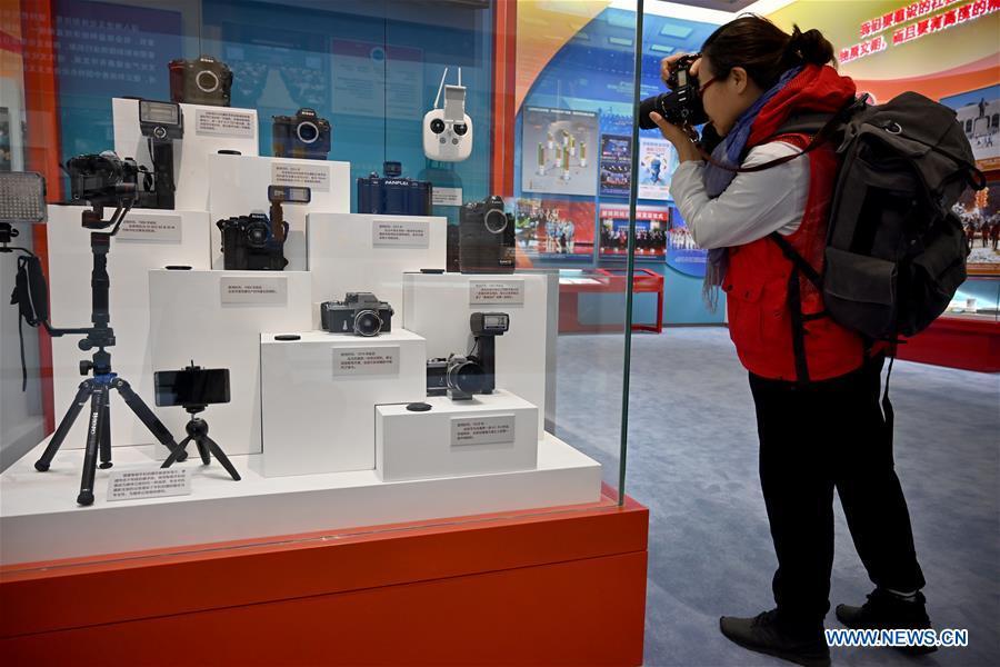 A visitor takes pictures of vintage cameras once used by Xinhua News Agency photographers which are displayed at a major exhibition to commemorate the 40th anniversary of China\'s reform and opening-up at the National Museum of China in Beijing, capital of China, Nov. 15, 2018. Vintage objects are displayed at the exhibition which opened here on Tuesday to show visitors the history, accomplishments, and experience of China\'s reform and opening-up. (Xinhua/Li Xin)