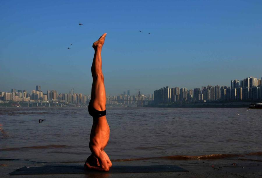 Wang Wanming, 61, a retiree in Southwest China\'s Chongqing municipality, has been practicing yoga almost every day by the Yangtze River for six years. His technique has made him a local celebrity. (Photo provided to chinadaily.com.cn)