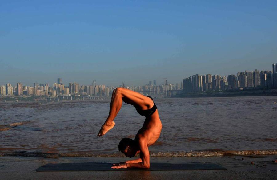 Wang Wanming, 61, a retiree in Southwest China\'s Chongqing municipality, has been practicing yoga almost every day by the Yangtze River for six years. His technique has made him a local celebrity. (Photo provided to chinadaily.com.cn)