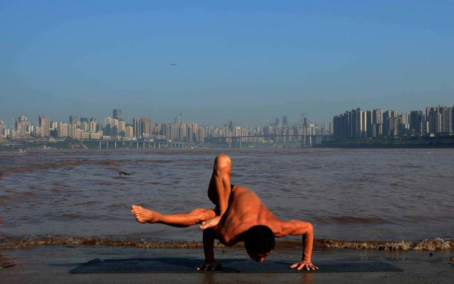 Wang Wanming, 61, a retiree in Southwest China\'s Chongqing municipality, has been practicing yoga almost every day by the Yangtze River for six years. His technique has made him a local celebrity. (Photo provided to chinadaily.com.cn)