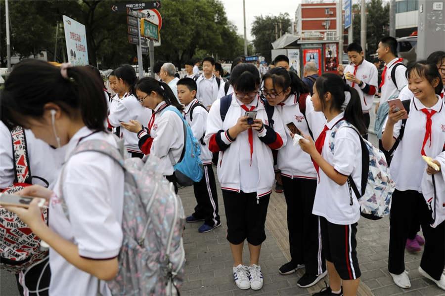 Students peer at their mobile phones while waiting to cross the road at Dongdaqiao in Beijing\'s Chaoyang district, Sept 18, 2018. (Photo provided to chinadaily.com.cn)