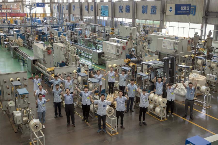 Workers pose for a group photo in the workshop of a cable production company in Suzhou city, East China\'s Jiangsu Province, July 31, 2018. (Photo provided to chinadaily.com.cn)