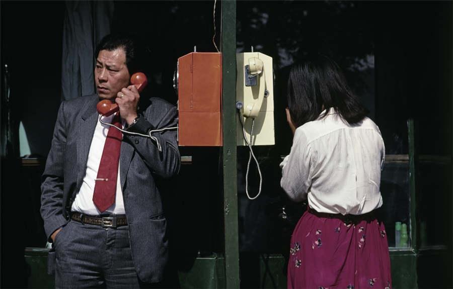 People use a telephone box by a road in Qianmen, Beijing, 1987 (Photo provided to chinadaily.com.cn)