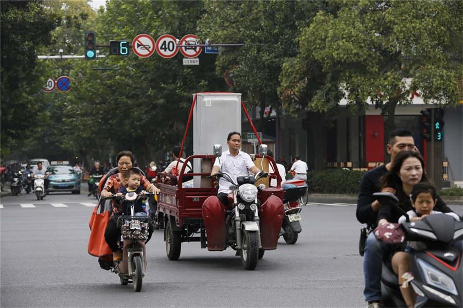 A man carries a refrigerator in a three-wheeled scooter on Guoqing Road, Yangzhou city, East China\'s Jiangsu province, Sept 22, 2018.  (Photo provided to chinadaily.com.cn)