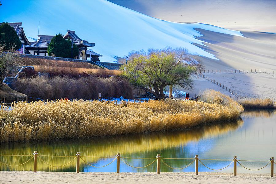 Dunhuang embraces this winter\'s first snowfall on Nov. 14. As the sun comes out, snow scenery in local landmark attractions like the Mingsha Mountain and Yueya Spring, a crescent-shaped spring-fed lake surrounded by desert, turns to a fairyland. (Photo/China Daily)