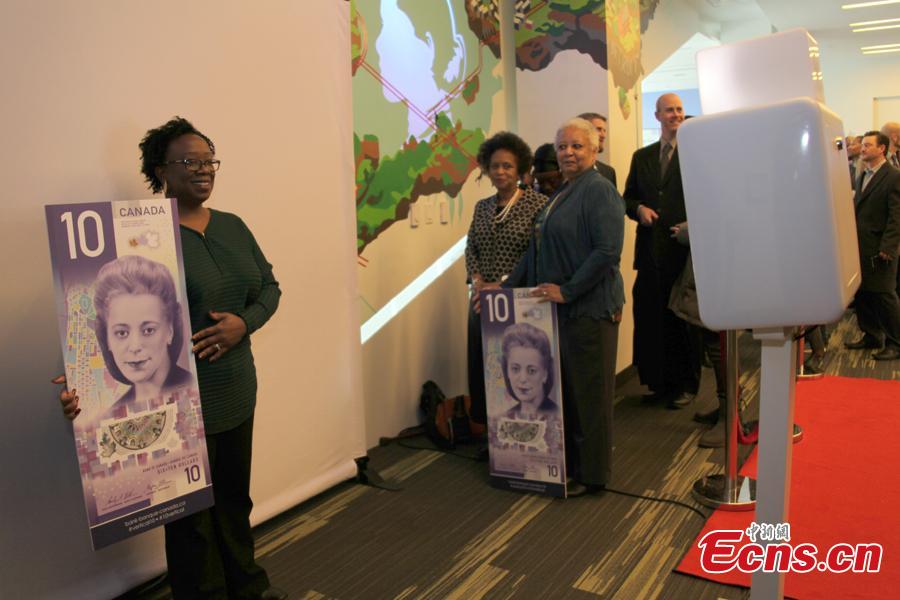 People pose for photo with a $10 banknote featuring Viola Desmond in Toronto, Canada, Nov. 19, 2018. The banknote is the first vertically oriented bill in Canada and the first regularly circulating banknote to feature a Canadian woman, civil rights advocate Viola Desmond, on the front. (Photo: China News Service/Yu Dongrui)
