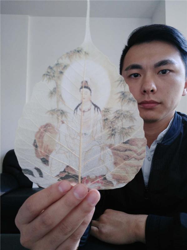 Ding Li takes a selfie with his artwork in his workshop in Xianning city, Hubei Province. (Photo provided to chinadaily.com.cn)

Leaf painting has a history of more than 2,000 years in China. A 27-year-old man Ding Li, from Xianning city of Hubei Province has devoted a dozen years to learning leaf art, and fuses ancient tattooing techniques into his creations. Ding has spent one year creating the ancient painting Along the River During the Qingming Festival which is painted on 10 pieces of michelia alba leaves.

Ding started to learn painting at 5, and began learning carving at 12. When he first found out about leaf painting at 13 years old, he became obsessed with the art.

The process of making leaf paintings is quite complicated. First the artist selects fine linden leaves or michelia alba leaves from mountains in Yunnan province, then go through over 60 steps such as cutting, soaking, pressing, sculpting, grinding, ironing and bleaching. The whole affair takes at least two to three months to finish.

Two of Ding\'s works won the silver award during a recent art exhibition between China and Japan on Oct. 28.

Before each creation, Ding will first learn related historical stories to make his artwork more detailed. \