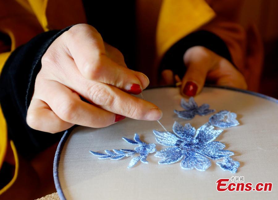 Liu Yao, a girl from northwestern China city Lanzhou, shows her embroidery works featuring patterns made of preserved flowers. With stitching techniques of Suzhou Embroidery and beading skills, the girl, an embroidery lover, makes her works with colorful dried flowers. (Photo: China News Service/ Gao Zhan)