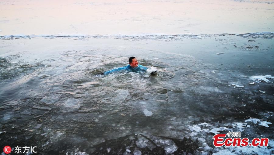 A winter swimming enthusiast broke the ice and jumped into the Songhua River to start his winter swimming season in Harbin, Northeast China\'s Heilongjiang province, on Nov 23, 2018. Hundreds of winter swimming enthusiasts swim in the river every year. (Photo/VCG)