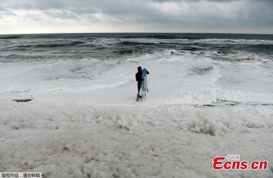 An Indian fisherman pulls in his fishing net as foamy discharge, caused by pollutants, mix with surf at a beach in Chennai on November 22, 2018.  High levels of sewage and industrial waste was claimed to be the cause of the foam, officials said. (Photo/Agencies)