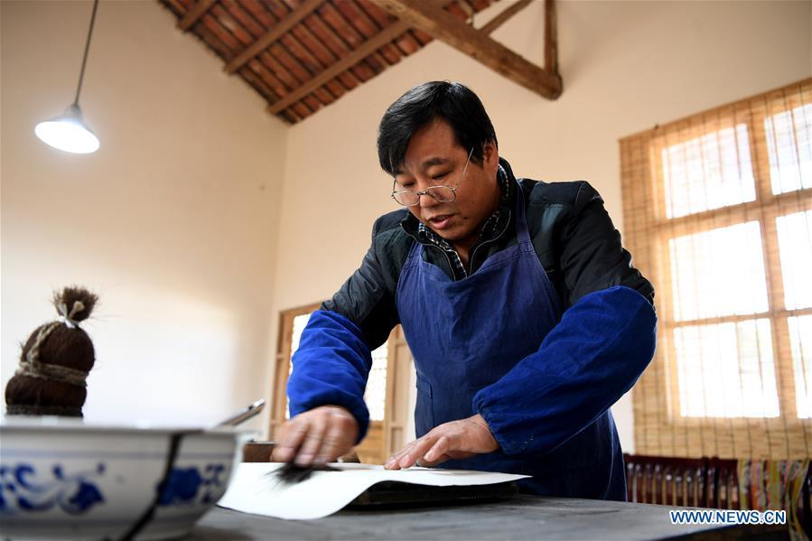 Lei Shitai works on a paper as he prints a book in Chanshan Village of Qinxi Town, Jingxian County, in east China\'s Anhui Province, Nov. 23, 2018. Lei, 52, born in neighboring Jiangxi Province, started his career as a typography printer when he finished his apprenticeship with his uncle who he followed since he was 17. The traditional printing method witnessed an increasingly hard time in the recent years as a livelihood. It was in 2017 when he decided to move to Chanshan at the invitation of Kai Yuanhong, a local cabinet maker, to cooperate in a broader way. Lei is now working with the traditional technique in a larger scale. (Xinhua/Zhang Duan)