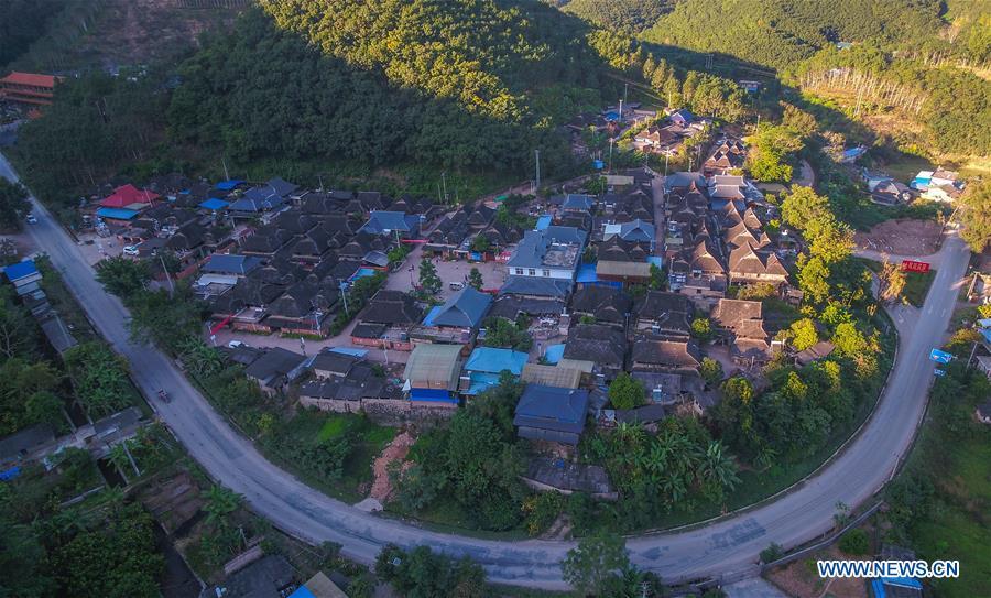 Aerial photo taken on Nov. 20, 2018 shows a corner of Bapiao Village in Jino Ethnic Township on Jino Mountain in Jinghong of Xishuangbanna Dai Autonomous Prefecture, southwest China\'s Yunnan Province. With a population of slightly over 20,000, the Jino people had only been officially acknowledged in 1979 as an independent ethnic group of China. Until 1949, most of them had lived for generations in primitive mountain tribes in southwest China\'s Yunnan Province. Over the four decades since it embraced the reform and opening-up policy, China has spared no effort to support ethnic groups with smaller populations. Life on Jino Mountain, where most Jino communities are located, saw positive changes in parallel with improvements in local politics, economy, technology, education, culture, health care, ecology, ethnic development and other social undertakings. Just like its 55 ethnic brethren, the Jino people also benefit from China\'s reform and opening-up in seeking a prosperous life. In Jino Ethnic Township on the Jino Mountain, residents now have direct access to road, water, electricity, TV and radio, as well as the mobile network. Ninety percent of the residents have moved into new houses. Most residents own motorcycles and tractors, and some of them have purchased cars. More people have increased their income by selling local specialty products via the internet, whereas in the past, doing business was perceived as a shame. Currently, the primary education in Jino Ethnic Township achieved 100 percent coverage for all school-age children. More than 99 percent of residents have joined the rural cooperative medical insurance programme. The Jino ethnic culture undergoes protection and inheritance: the great drum dance of the Jino people has been listed as one of China\'s national intangible cultural heritages. (Xinhua/Yang Muyuan)