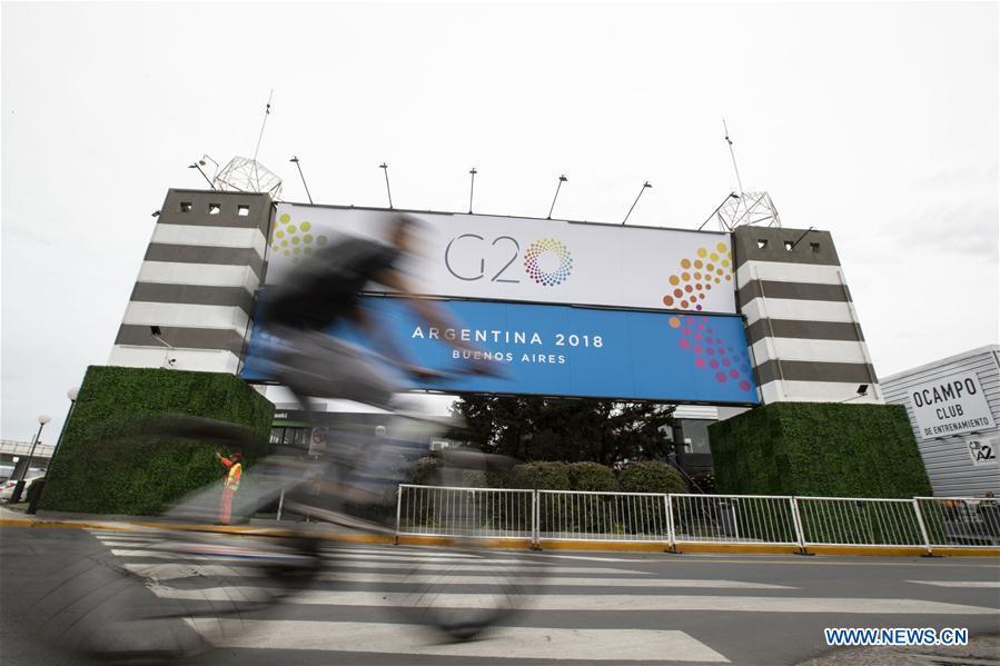 A man rides a bicycle past a banner of G20 summit outside the Costa Salguero Center in Buenos Aires, Argentina, on Nov. 27, 2018. The 13th G20 summit, under the theme of Building Consensus for Fair and Sustainable Development, will be held for the first time in a South American country from Friday to Saturday. (Xinhua/Li Ming)