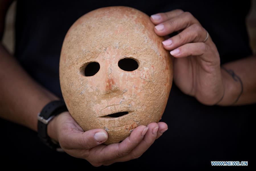 Ronit Lupu, an archeologist from the Israel Antiquities Authority (IAA), holds a stone mask at the Rockefeller Museum in Jerusalem, on Nov. 28, 2018. A rare pre-historic stone mask, dating back to the Pre-Pottery Neolithic B (PPNB) period 9,000 years ago, was discovered in the southern West Bank, the Israel Antiquities Authority said Wednesday. (Xinhua/JINI)