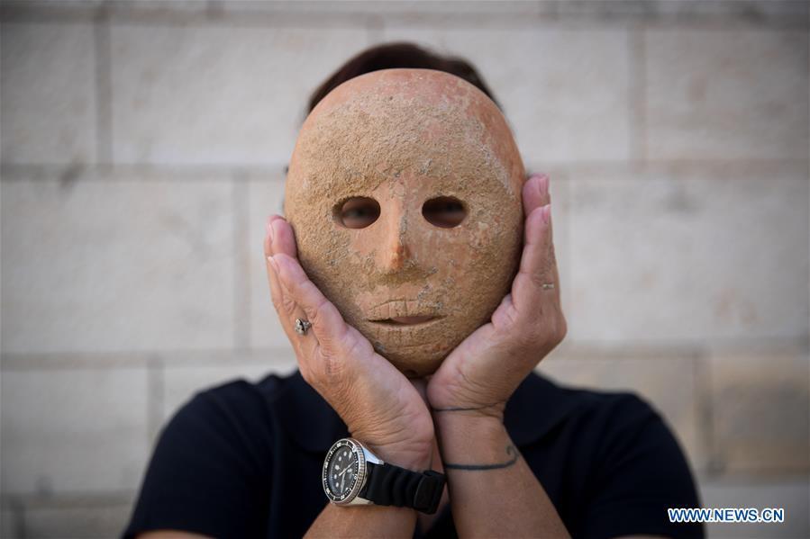 Ronit Lupu, an archeologist from the Israel Antiquities Authority (IAA), holds a stone mask at the Rockefeller Museum in Jerusalem, on Nov. 28, 2018. A rare pre-historic stone mask, dating back to the Pre-Pottery Neolithic B (PPNB) period 9,000 years ago, was discovered in the southern West Bank, the Israel Antiquities Authority said Wednesday. (Xinhua/JINI)