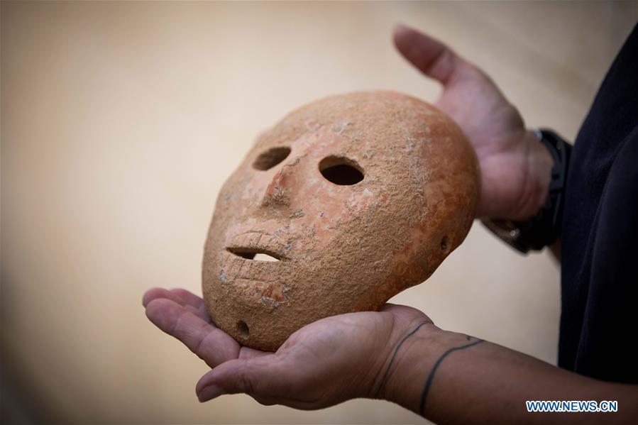 Ronit Lupu, an archeologist from the Israel Antiquities Authority (IAA), holds a stone mask at the Rockefeller Museum in Jerusalem, on Nov. 28, 2018. A rare pre-historic stone mask, dating back to the Pre-Pottery Neolithic B (PPNB) period 9,000 years ago, was discovered in the southern West Bank, the Israel Antiquities Authority said Wednesday. (Xinhua/JINI)