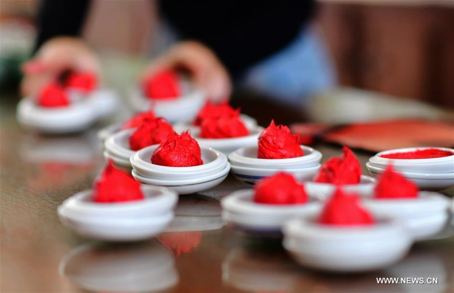 A worker fills Babao red ink paste into saucers in Zhangzhou, southeast China\'s Fujian Province, Nov. 30, 2018. Made of many precious materials such as pearl, agate, coral and musk, Zhangzhou red ink paste has been favoured by painters and calligraphers both home and abroad for over 300 years. Its making technology was listed as the second batch of national intangible cultural heritages in 2008. (Xinhua/Wei Peiquan)