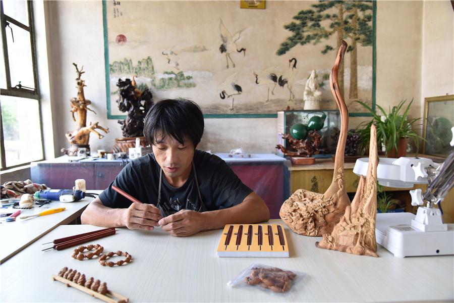 Zhu Haiyang does olive pit carving at his home in September of last year. (Photo by Qian Lei for chinadaily.com.cn)
Zhu Haiyang, 40, a farmer in Beijing\'s Miyun district, is making money through olive pit carving artwork this year, with support from the local government.
Due to his old-fashioned tools, Zhu\'s output is limited. He could only carve a few pieces to sell last year, which was not enough to support his family.
Last September, the local government subsidized Zhu by upgrading his tools and carving machines, greatly raising his efficiency.
Zhu said the orders he can handle in one month is now equal to the number of orders he could take for a whole year before.
\