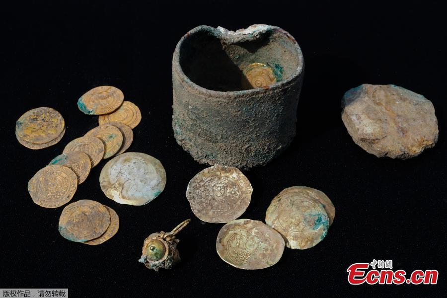 A picture taken on December 3, 2018, shows ancient gold coins and an earring recently uncovered at an excavation site in the Israeli Mediterranean town of Caesarea.  A treasure of 24 rare gold coins consisting of 18 Fatimid dinars, which were the standard local currency during that time (909-1171), as well as six are Byzantine coins, which include five dating to the era of Byzantine Emperor Michael VII Doukas (1071-1078), was recently uncovered in Caesarea. (Photo/Agencies)