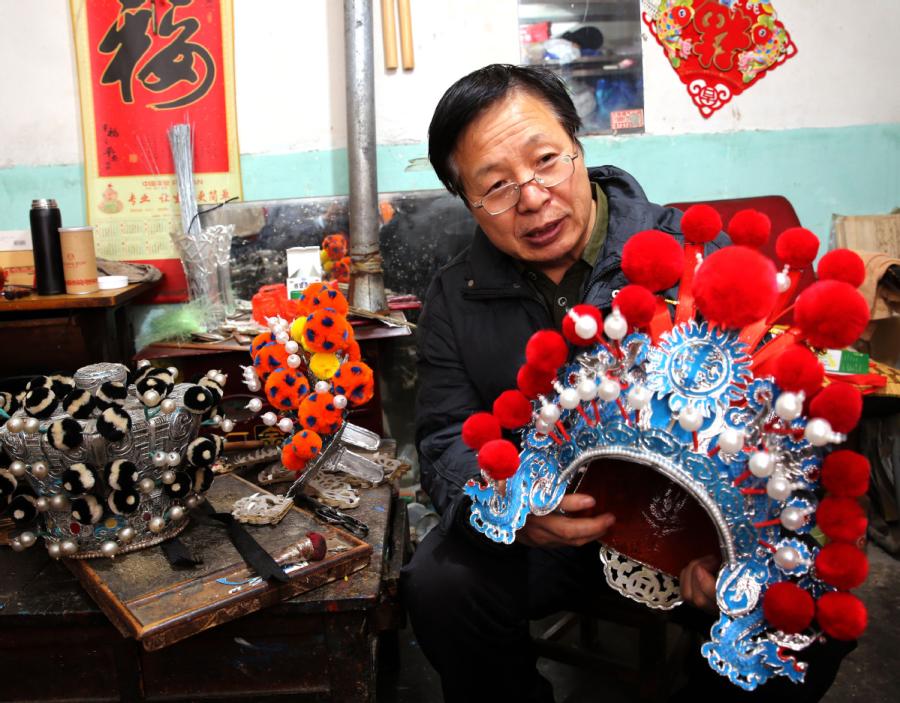 Han Xiaoli presents a headwear piece he made. (Photo by Huo Yan/chinadaily.com.cn)
Han Xiaoli, a 55-year-old craftsman from Xi\'an, capital of Northwest China\'s Shaanxi Province, can make more than 100 kinds of headwear for a local opera.
The unique headwear plays quite an important role in performances of qinqiang opera, a typical Shaanxi folk opera that requires performers to sing at a high pitch.
Han learned the skills from his father at the age of 15, and since then he has devoted his life to the intangible culture heritage.
\