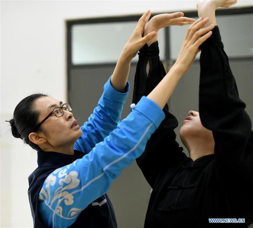 Huo Jinghong, the 5th generation descendant of Huo Yuanjia, a Chinese martial arts master, instructs a student to practice health Qigong, a traditional martial art combined with meditation, at Tianjin University of Commerce in Tianjin, north China, Nov. 26, 2018. As the descendant of Huo Yuanjia, one of China\'s most revered martial arts masters, Huo Jinghong, 41, started practicing martial arts at the age of 5. After her graduation from the Wushu School of Beijing Sport University in major of Wushu Routine, Huo started her career as a gym teacher of Tianjin University of Commerce in the year of 2000. As a gym teacher, Huo teaches martial arts for the university team and offers classes on health Qigong, a new form selected from different versions of traditional Qigong for modern fitness, in the university. Later in 2015, Huo became the inheritor of Huo-style boxing, which was listed as an intangible cultural heritage in Tianjin, and since then, she has devoted herself to the inheritance and development of the martial arts handed down from the older generation of Huo\'s family. She hoped that the Huo-style boxing would help people understand more about the Chinese martial arts. Huo Yuanjia was born in Tianjin in 1868. He founded the Chin Woo Athletic Association in 1910 in Shanghai and advocated the spirit of \