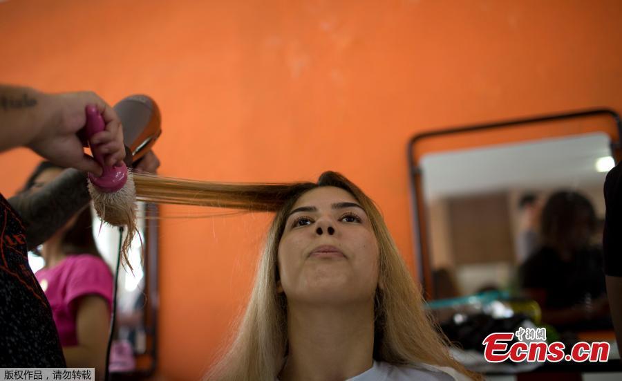 A hairstylist blow drys the hair of an inmate in preparation for the 13th annual Miss Talavera Bruce beauty pageant at the penitentiary the pageant is named for, in Rio de Janeiro, Brazil, Tuesday, Dec. 4, 2018. Hairdressers and makeup artists volunteer their time to ready the contestants who are judged on their beauty, appeal and attitude. (Photo/Agencies)