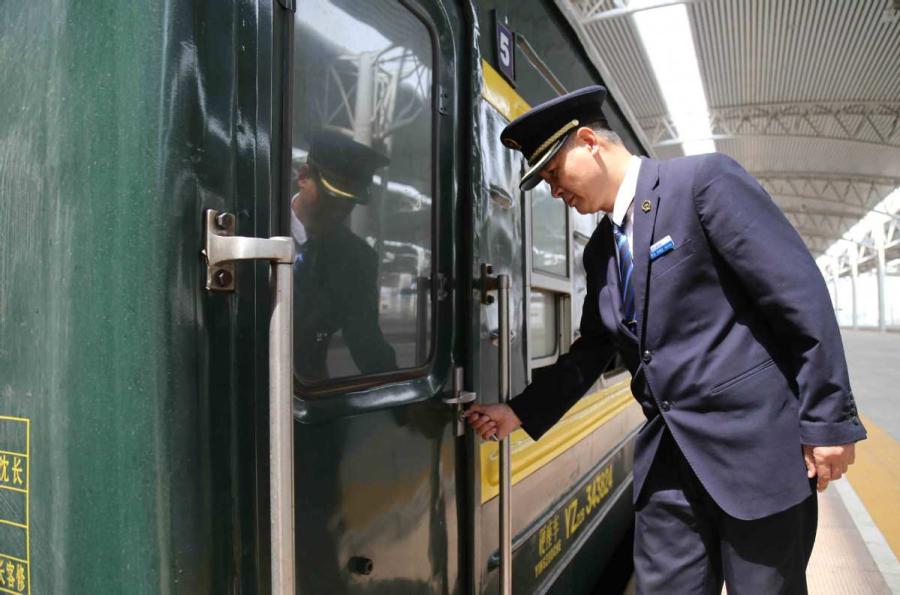 Sun Mingjin opens the door of a green train carriage. (Photo by Qu Xiaoxi for chinadaily.com.cn)