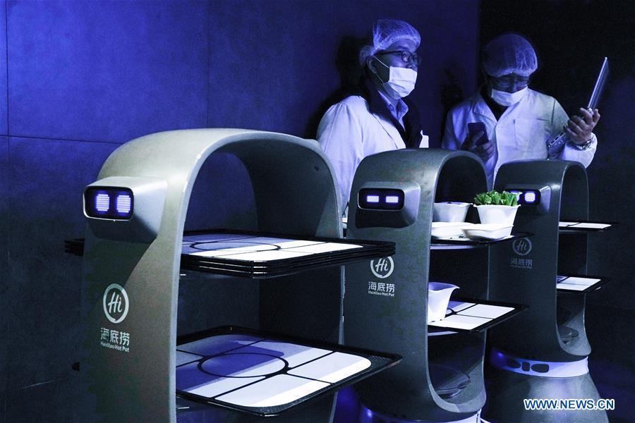 Technicians manage intelligent equipment at a hot pot restaurant in Beijing, capital of China, Dec. 5, 2018. A hot pot restaurant which integrates artificial intelligence, big data management and smart robot service has attracted lots of consumers. After customers order their dishes with a tablet computer, robotic arms in the kitchen get all dishes ready and then the delivery robots sent the dishes to the tables. Workers in the kitchen control all the procedures and also monitor the data for better management. (Xinhua/Chen Junqing)