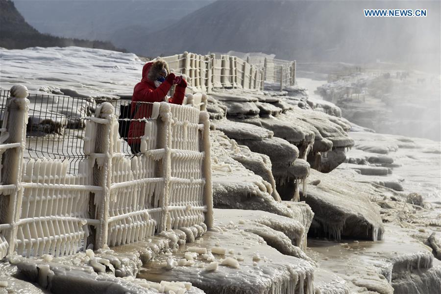 A visitor takes photos of icicles at the Hukou Waterfall scenic spot of the Yellow River at the border area between north China\'s Shanxi Province and northwest China\'s Shaanxi Province on Dec. 7, 2018. (Xinhua/Lyu Guiming)