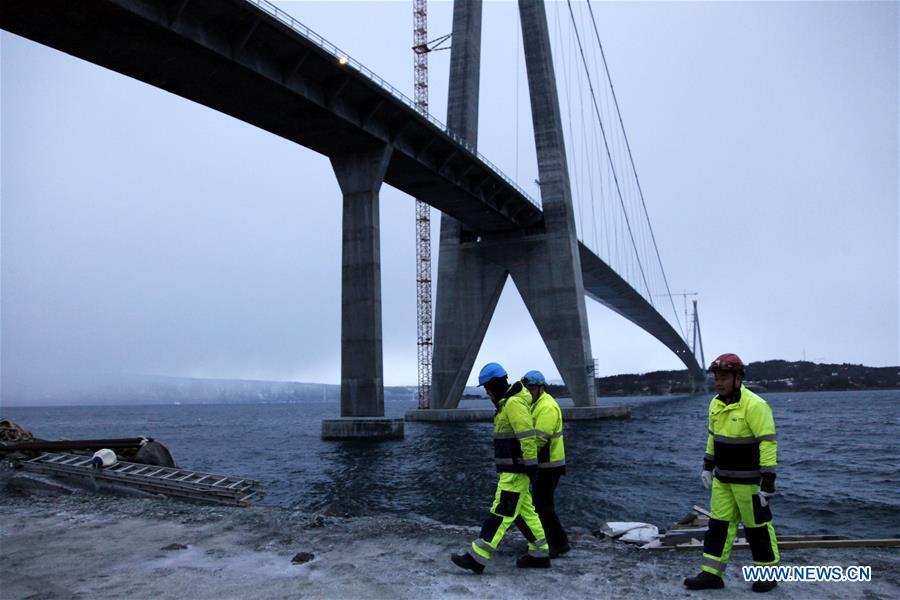 Chinese workers walk beneath the Halogaland Bridge near Norway\'s northern port city of Narvik, Dec. 9, 2018. A ceremony was held Sunday to officially open Norway\'s second largest bridge that has been built by a Chinese company and its partners some 220 km inside the Arctic Circle. With a total length of 1,533 meters and a free span of 1,145 meters, the Halogaland Bridge near Norway\'s northern port city of Narvik is the longest suspension bridge within the Arctic Circle. (Xinhua/Liang Youchang)