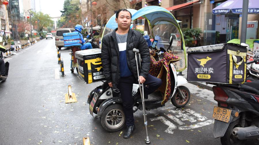Chen Dengchao, 29, a delivery man in southwest China\'s Chongqing, stands in front of his electric tricycle. (Photo by Li Jiaqi for chinadaily.com.cn)
Chen Dengchao jumped from his electric tricycle and landed on his right foot, holding tightly a takeaway parcel. Aided by a crutch, he walked faster than many able-bodied people.
The 29-year-old in southwestern China\'s Chongqing city suffered poliomyelitis after he was born in Qiantang township, Hechuan district. Due to poor medical treatment, his left leg was disabled when he was 12.
After working as a repairman and a web manager, he became a delivery man in downtown Chongqing in September last year.