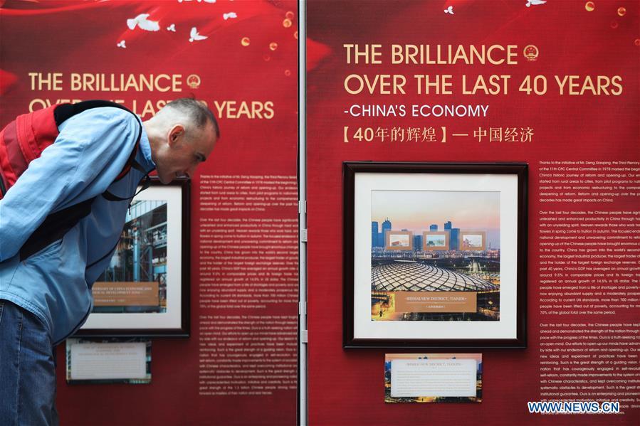 A visitor watches the stamps showing China\'s economic achievements during the \